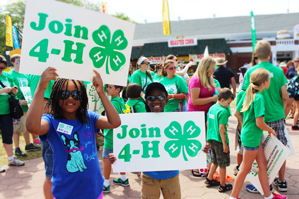 Children holding up signs stating "Join 4-H"