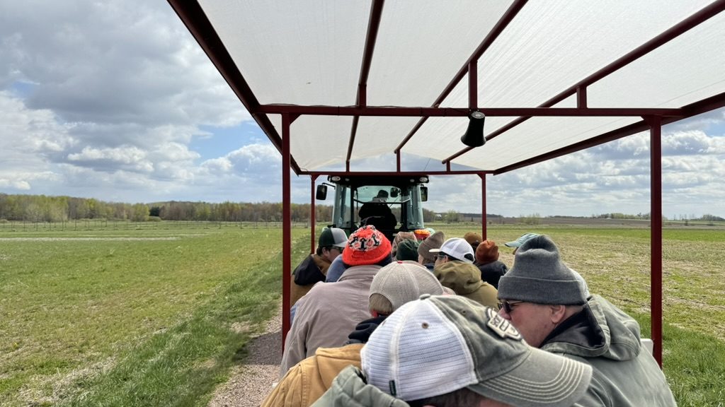 Image of people riding a wagon with a tractor in front going through a field