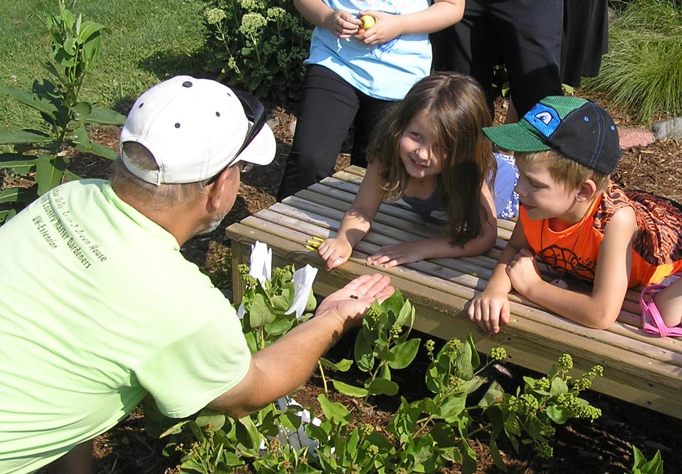 A Master Gardener explaining something to two children