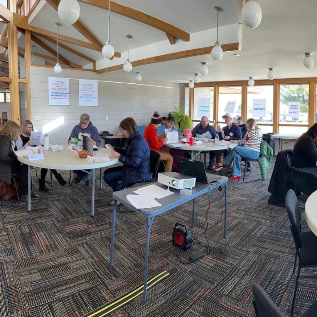 Classroom with people sitting at tables watching a presentation